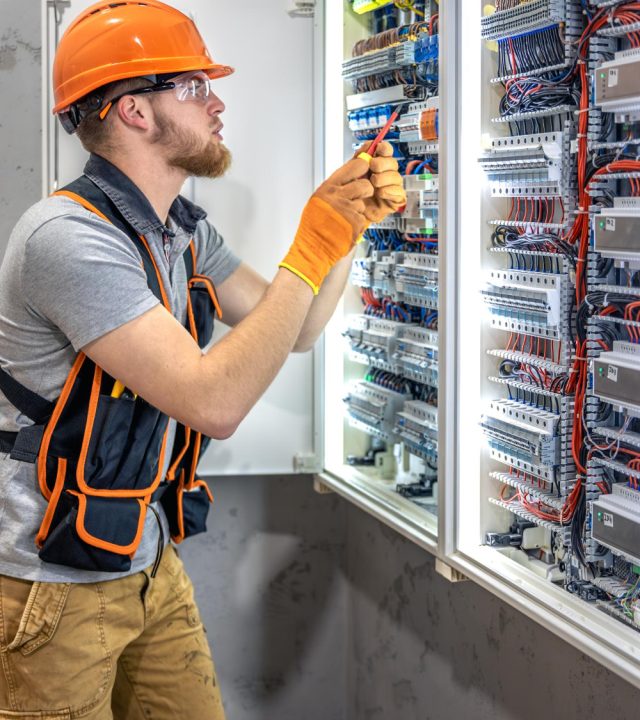 Électricien homme travaillant sur un tableau électrique, électricien homme en salopette